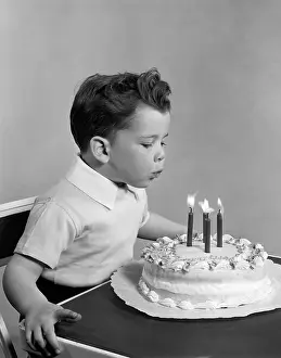 1950s Prints: Boy blowing out candles on cake, c.1950s, Vintage Nostalgia